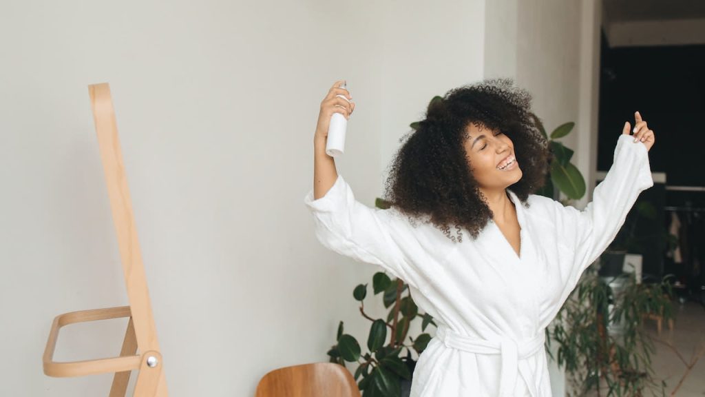 Woman in Bath Robe Holding Hair Shampoo Spray