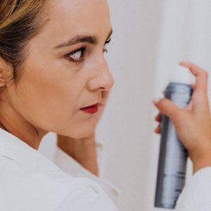 Woman in White Using Dry Shampoo