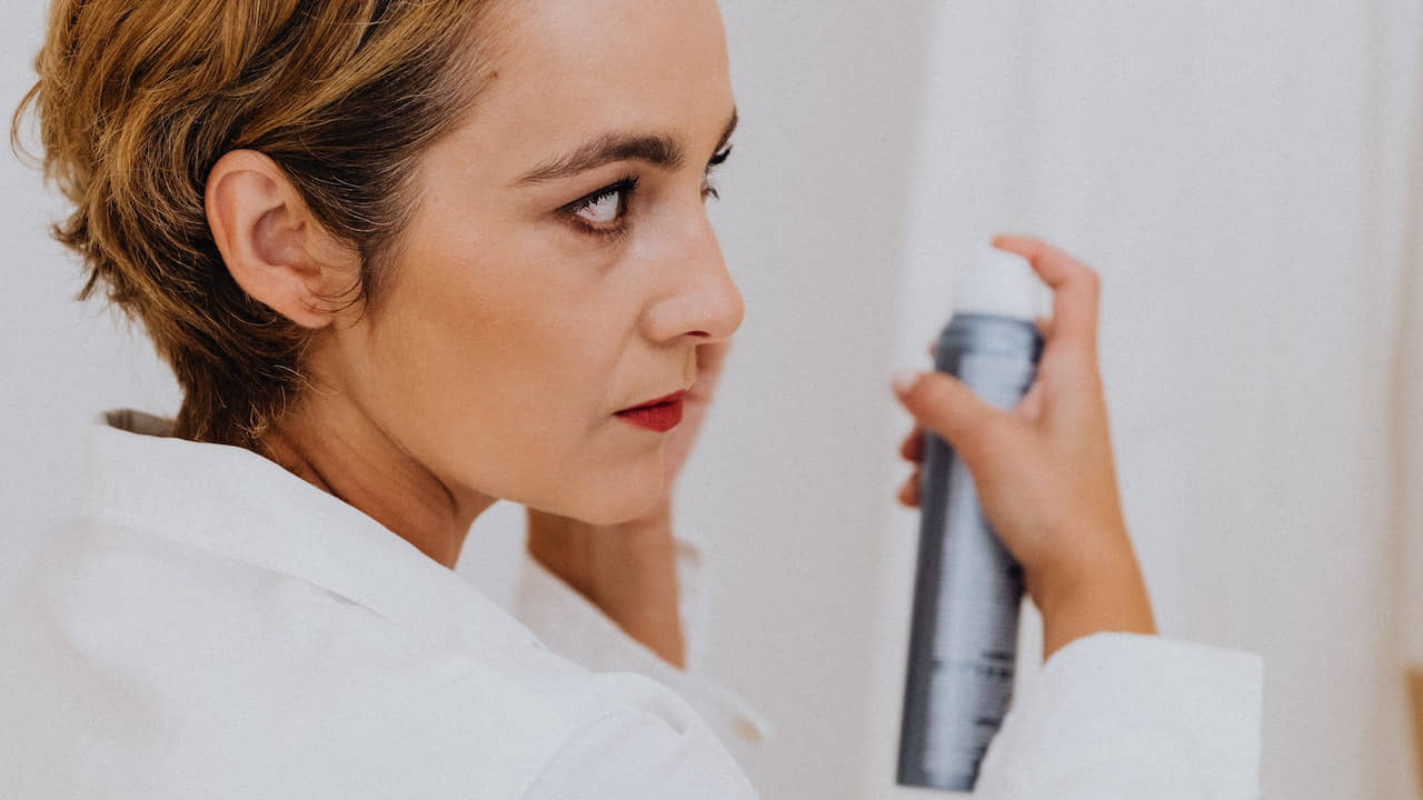 Woman in White Using Dry Shampoo