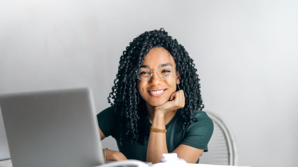 Happy woman sitting at table with laptop