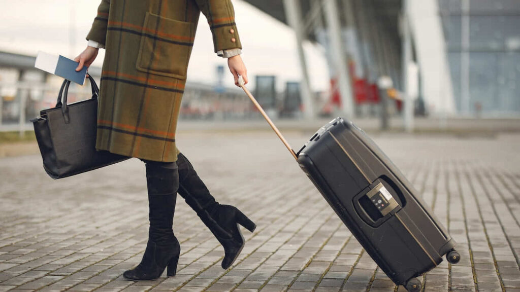 Woman Walking on Pathway While Strolling Luggage