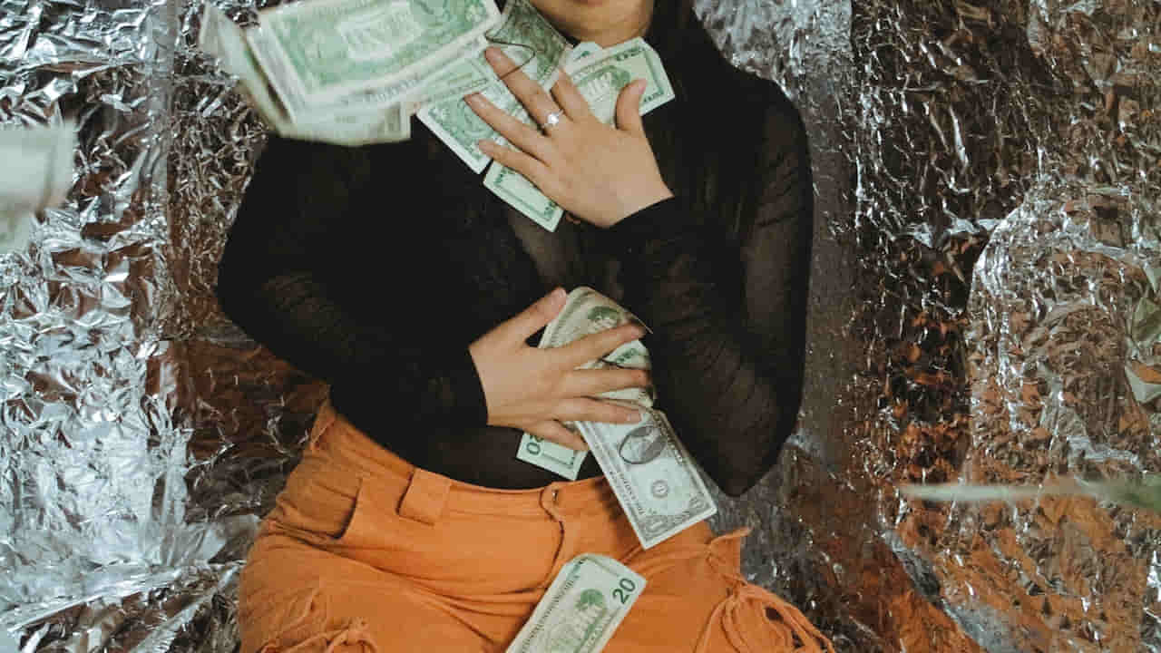 Young woman with money sitting on floor