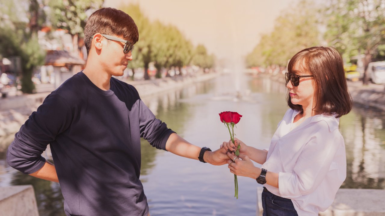 A man handing a rose to a woman which is a form of love language