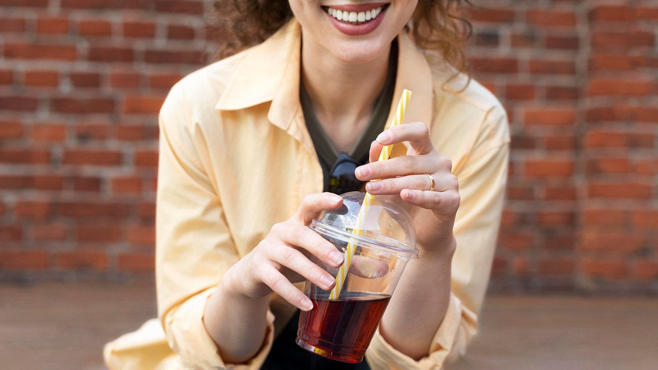 Close-up of a women holding a cup with a straw